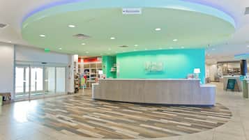 A hotel reception area with a curved counter, a sign for restrooms, and a view of the lobby.