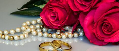 Un ramo de rosas rojas, una hebra de perlas y dos anillos de oro con un diamante.