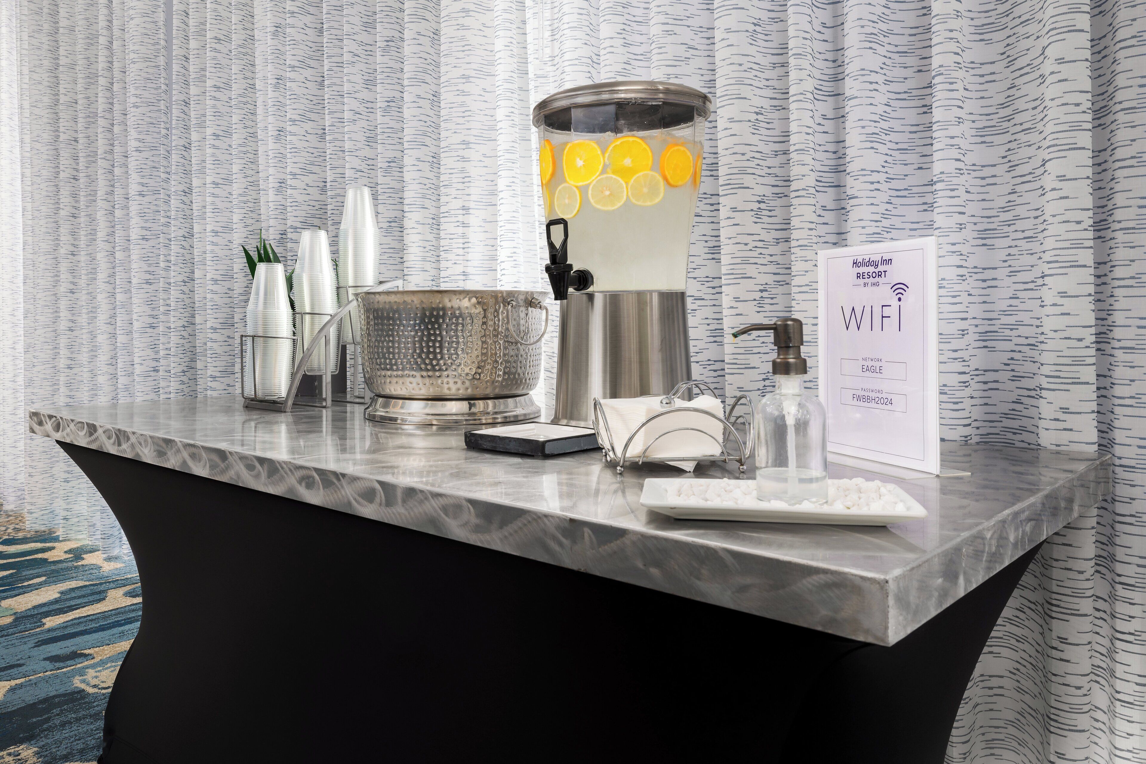 A hotel reception desk with a water dispenser, a scale, a tray, and a sign indicating WIFI availability.
