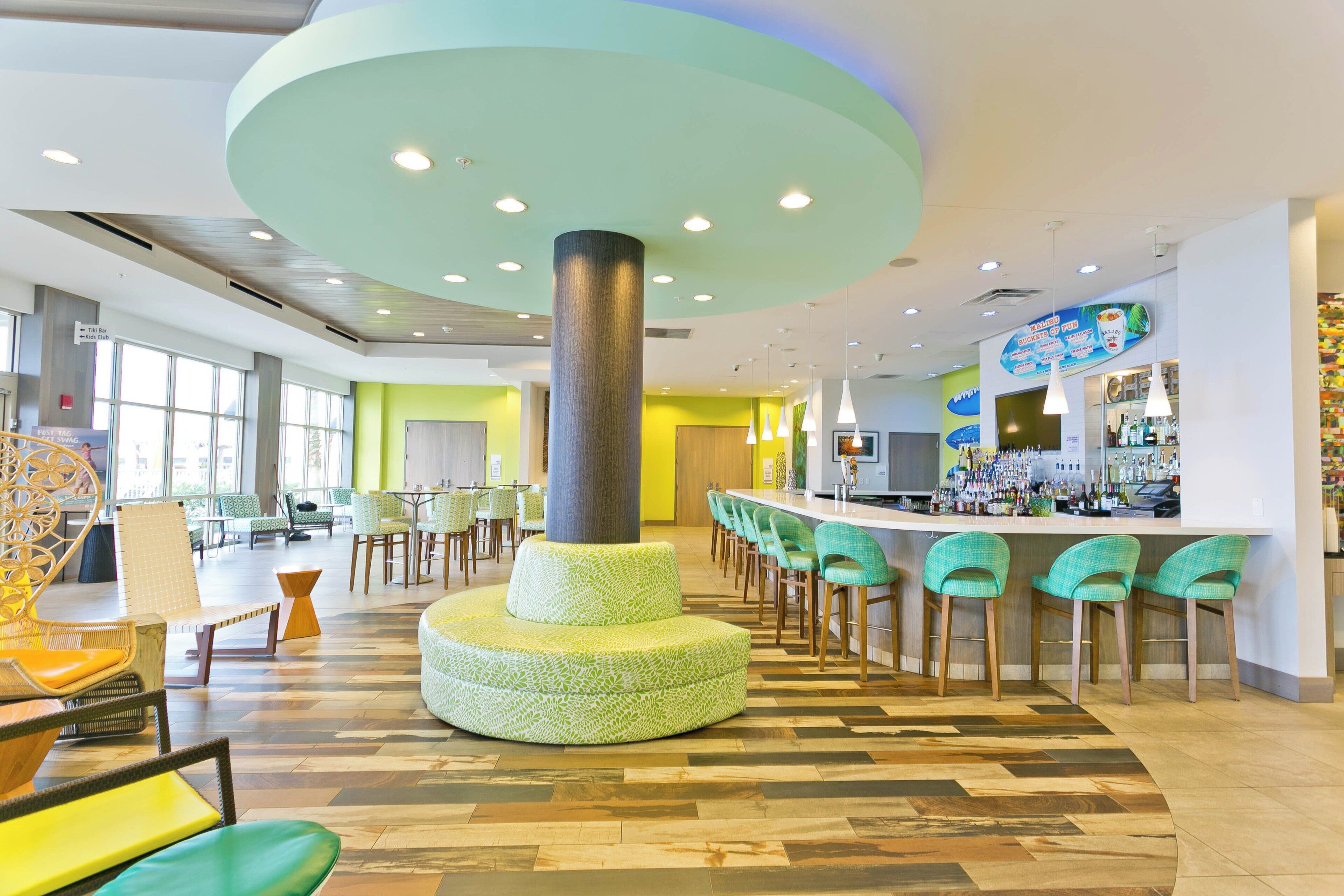 A modern bar area with a central column, seating, and a bar counter.