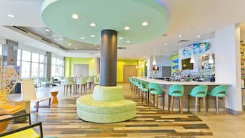 Un área de bar moderna con una columna central, asientos y una barra.
