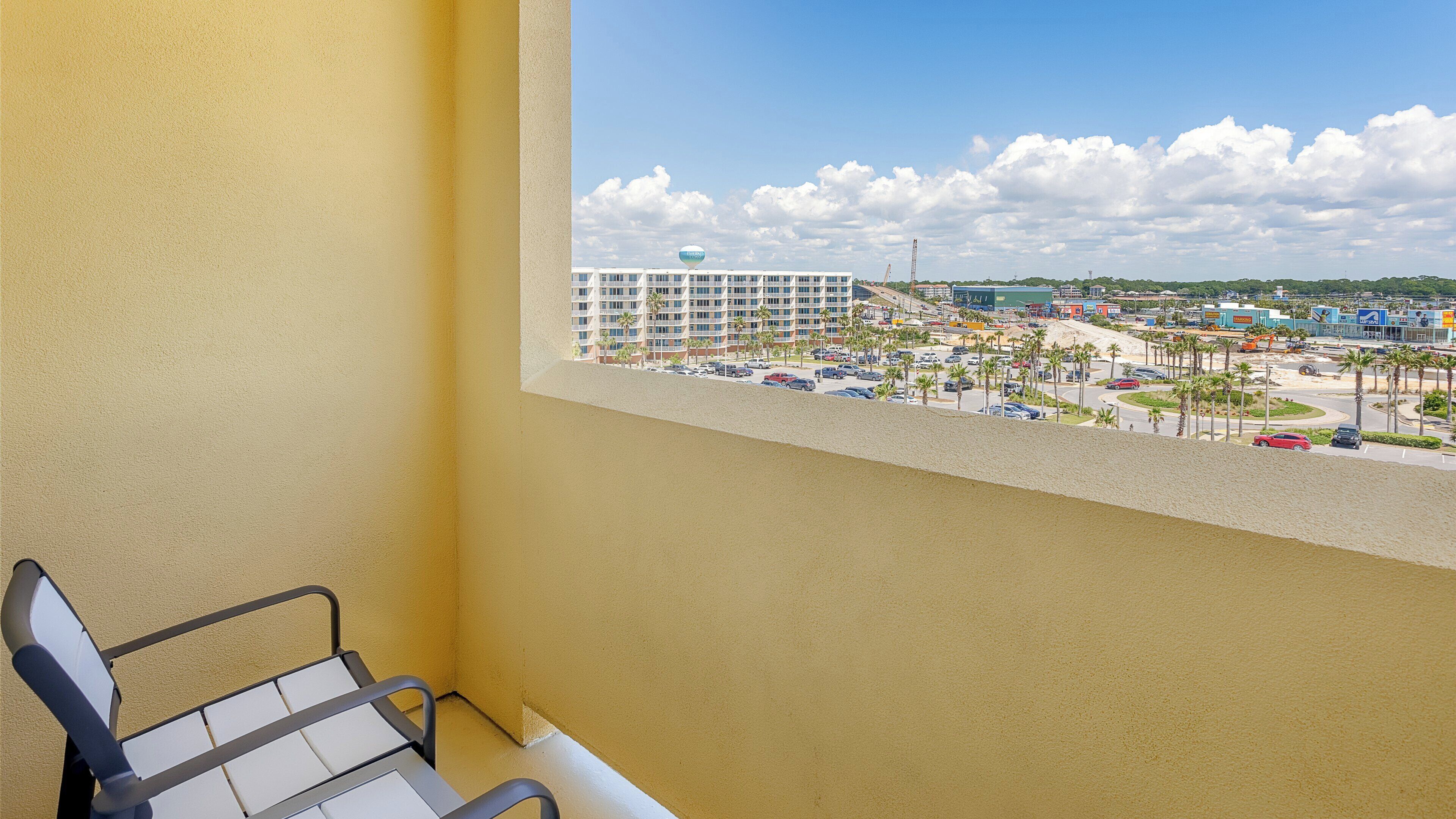 En balkon med udsigt over et hotel, en parkeringsplads og en byggeplads.