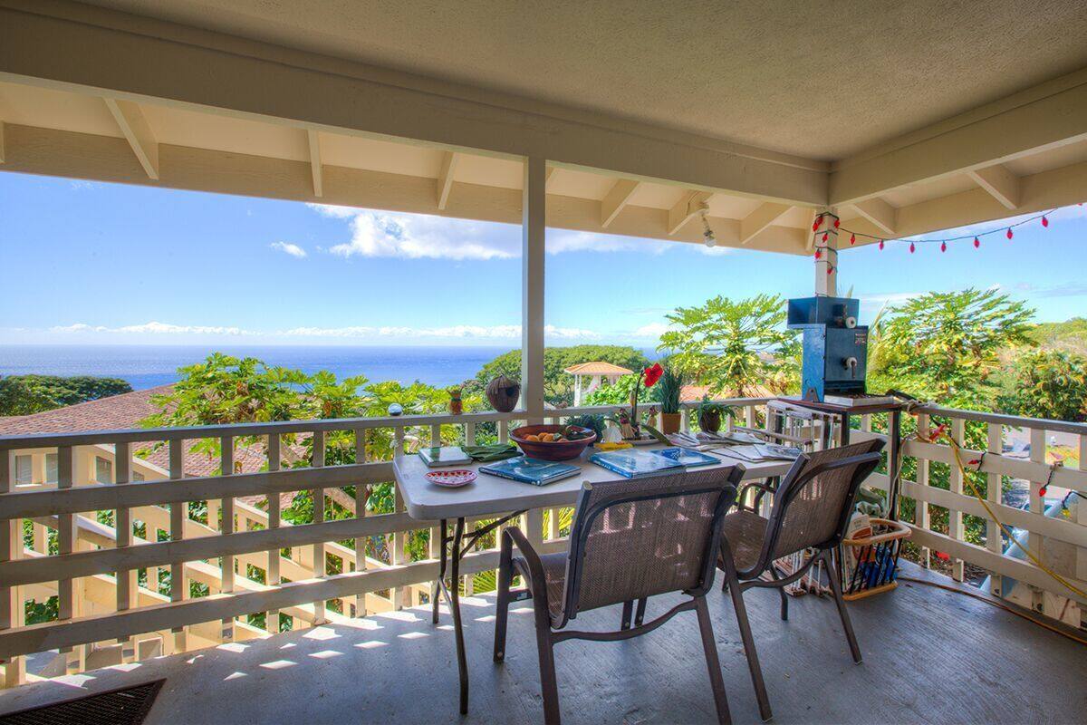 A balcony with a table, chairs, and a grill.