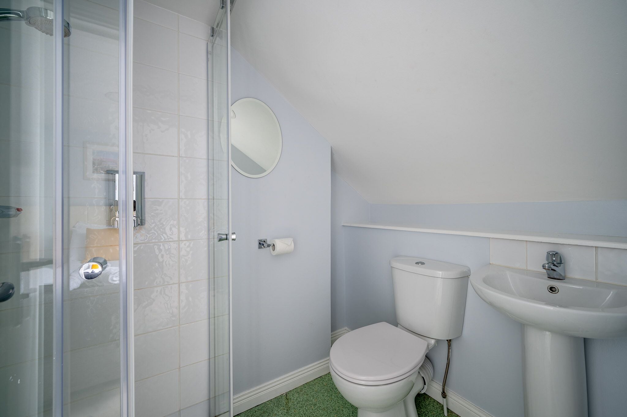 A bathroom with a toilet, sink, and glass shower enclosure.