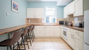 A kitchen with white cabinets, a wooden countertop, a microwave, a toaster, and a window with a view.