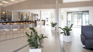 A spacious lobby with a bar area, seating, and potted plants.