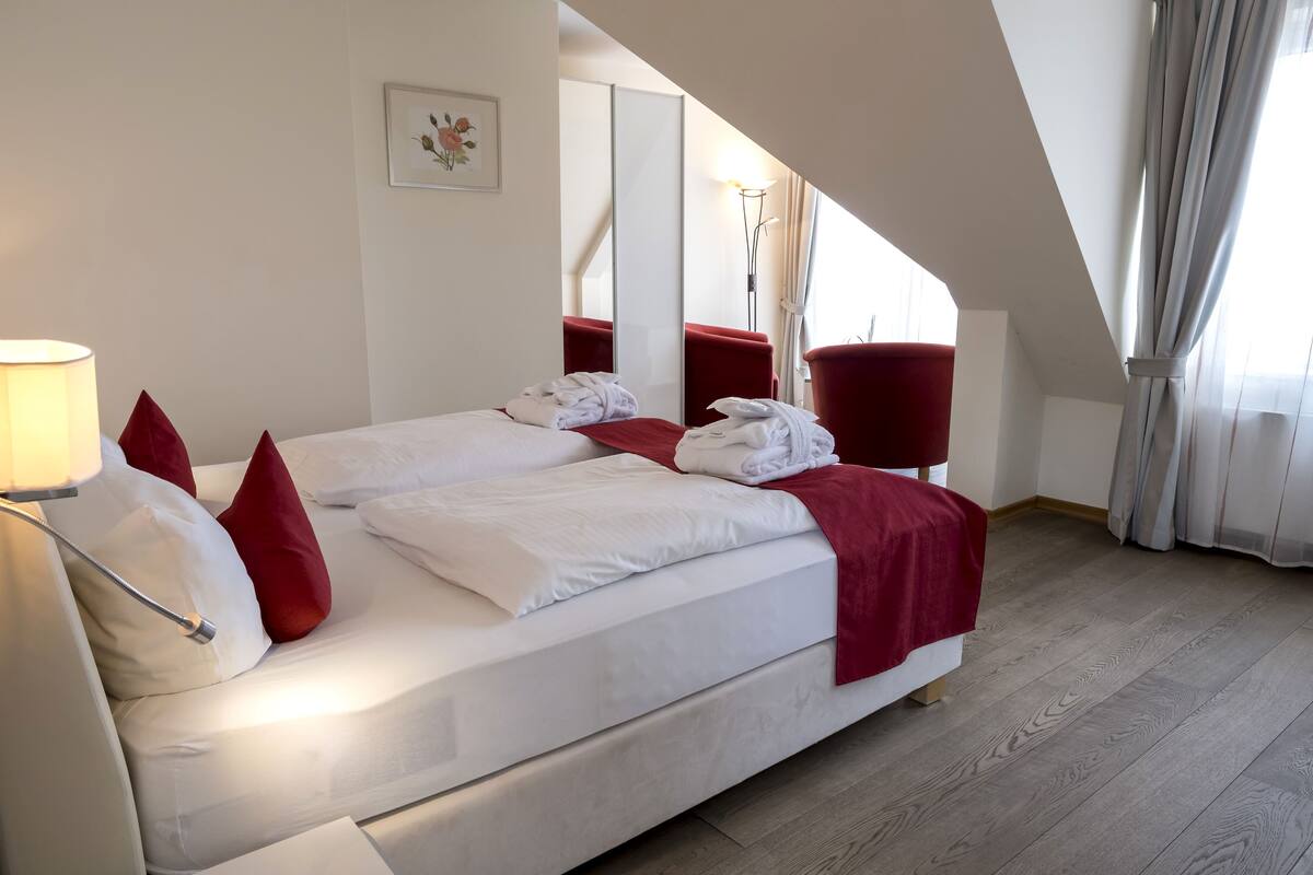 Een hotelkamer met een bed, een rode stoel, een spiegel en een lamp.