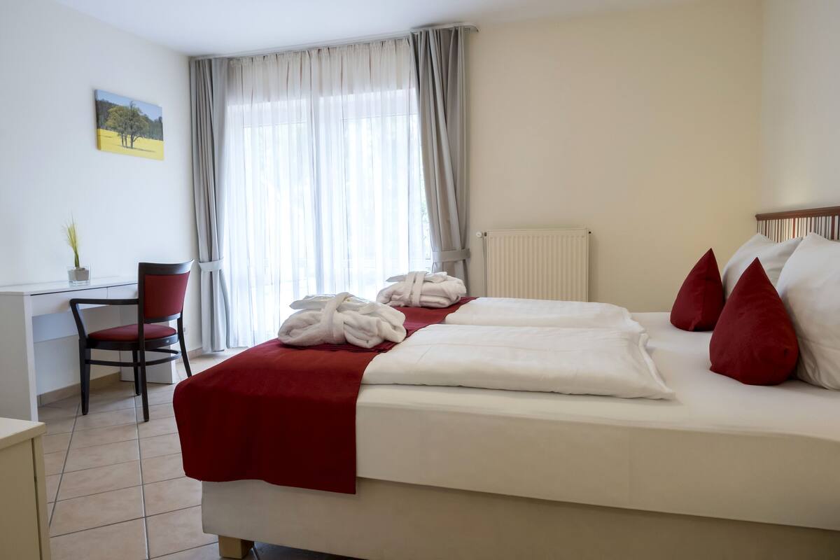 Een hotelkamer met een bed, een bureau, een stoel en een raam met gordijnen.