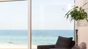 A living room with a large window overlooking a beach.