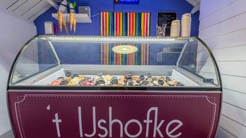 An ice cream shop named 't Ushofoe' with a variety of colorful ice cream cones and toppings displayed in a glass case.
