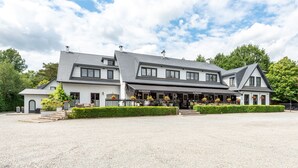 A two-story building with a gravel driveway and a well-maintained hedge in front.