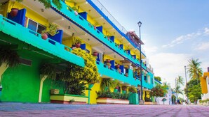 A multi-story building with balconies, potted plants, and a clear sky. - Posada Real (Rincón de Guayabitos)