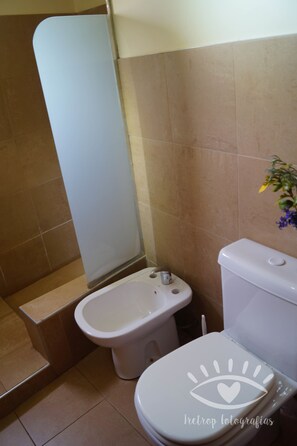 A bathroom with a toilet, bidet, and a shower area. - Monte Coiron (Malargüe)