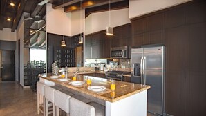 A modern kitchen with a central island, stainless steel appliances, and bar stools. - Pinnacle Resorts 180 (Puerto Vallarta)