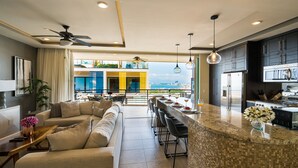 A modern kitchen with a large island, bar seating, and a view of the city. - Pinnacle Resorts 180 (Puerto Vallarta)