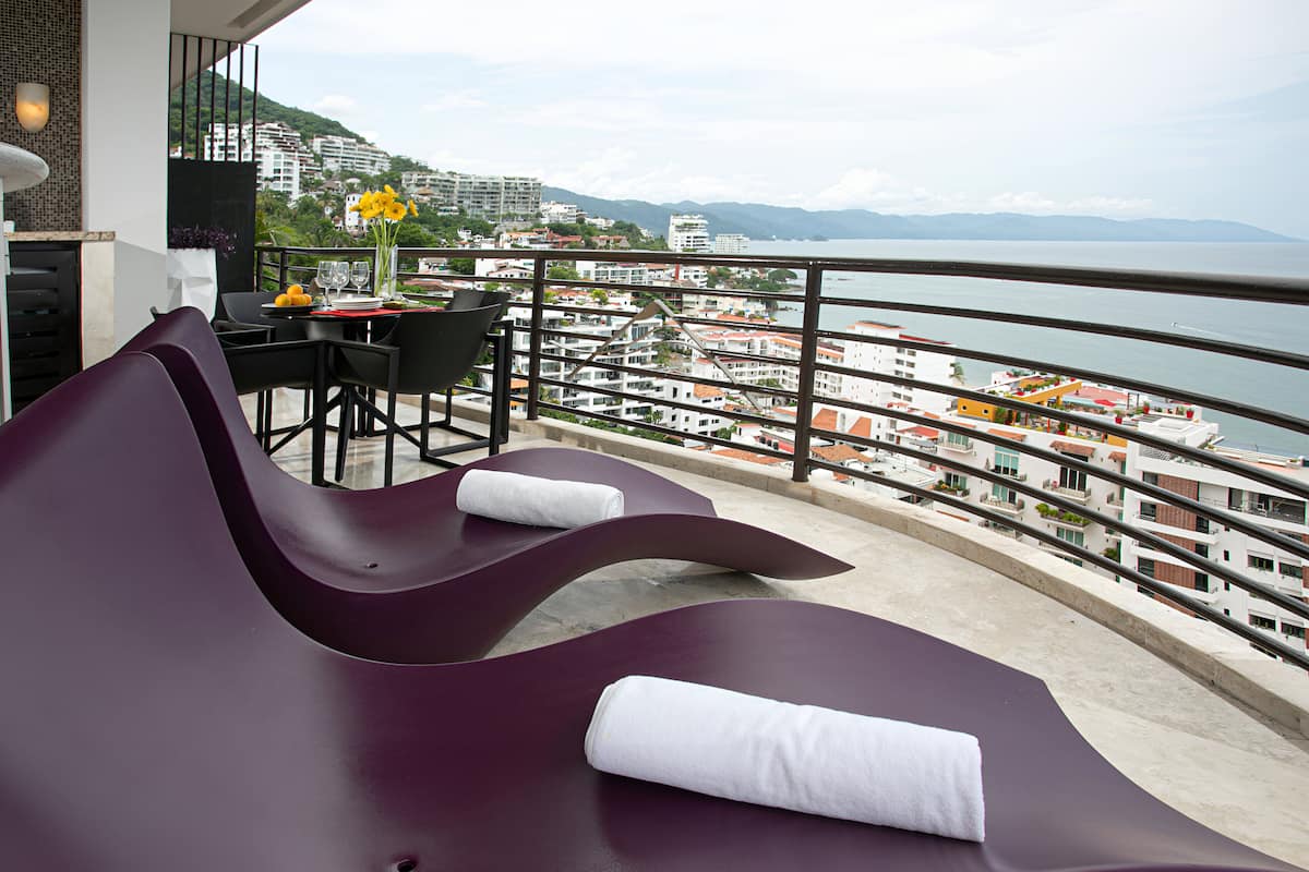 A modern outdoor seating area with a view of the sea and cityscape.