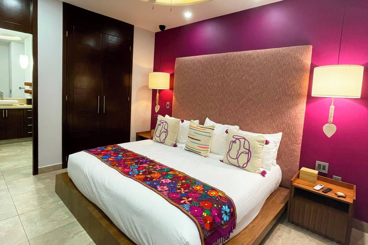 A modern bedroom with a large bed, a ceiling fan, and a nightstand with a lamp.