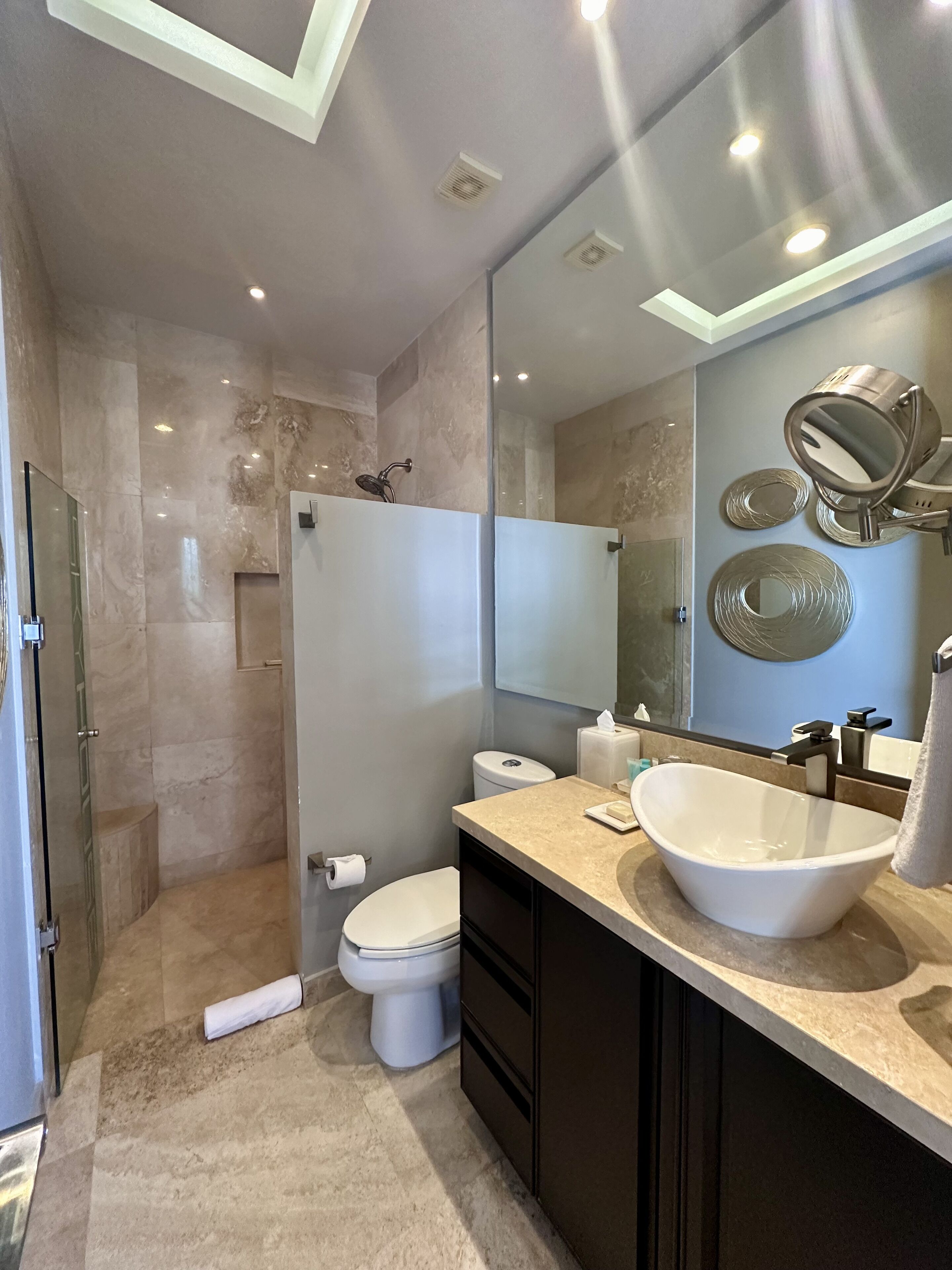 A modern bathroom with a large sink, mirror, and shower.