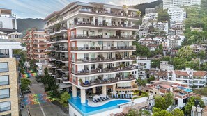 Ein mehrstöckiges Hotel mit Balkonen, einem Pool und Blick auf die umliegende Nachbarschaft.
