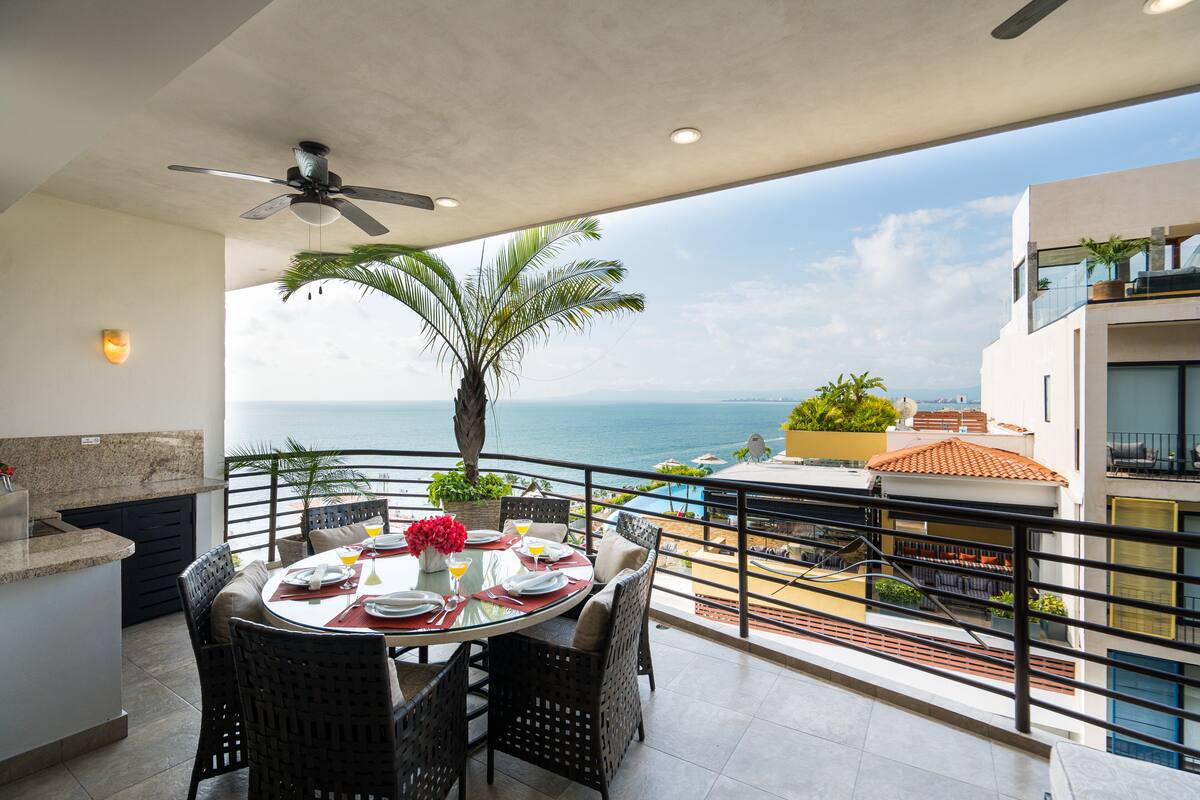 A balcony with a dining table, chairs, and a ceiling fan.