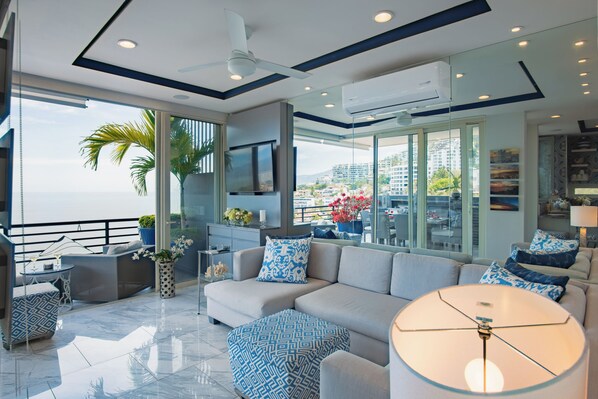 A modern living room with a sofa, ottoman, and a glass coffee table.
