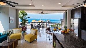 A modern kitchen with a view of the ocean, yellow sofas, and a dining area with a table and chairs. - Pinnacle Resorts 180 (Puerto Vallarta)