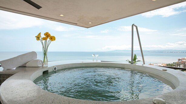 A hot tub with a view of the sea, a vase with flowers, and a towel. - Pinnacle Resorts 180 (Puerto Vallarta)