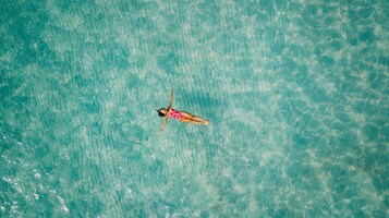 A person floating on a clear turquoise body of water.