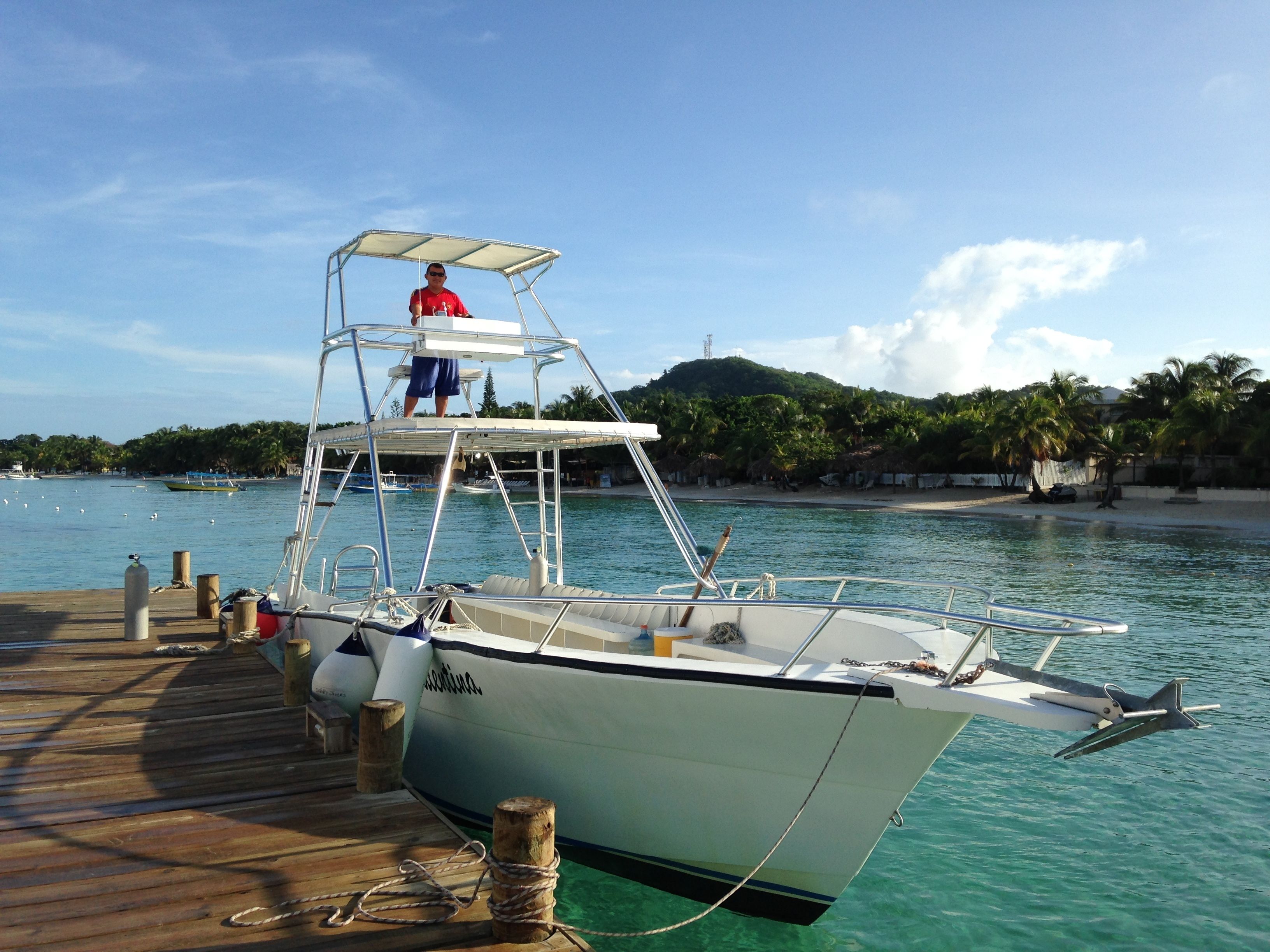 A boat docked at a pier with a clear view of the water and a beach in the background.