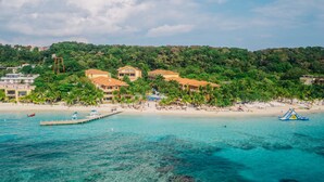 A coastal resort with multiple buildings, a beach, and clear turquoise waters. - Infinity Bay Spa & Beach Resort (Roatan)
