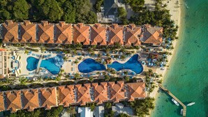 An aerial view of a resort with multiple swimming pools, a beach, and a pier. - Infinity Bay Spa & Beach Resort (Roatan)