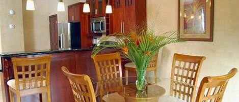 Una cocina con armarios de madera, una isla de vidrio y una mesa de comedor con sillas.