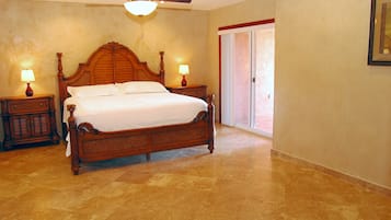 A bedroom with a wooden bed, two nightstands with lamps, a ceiling fan, and a large window.