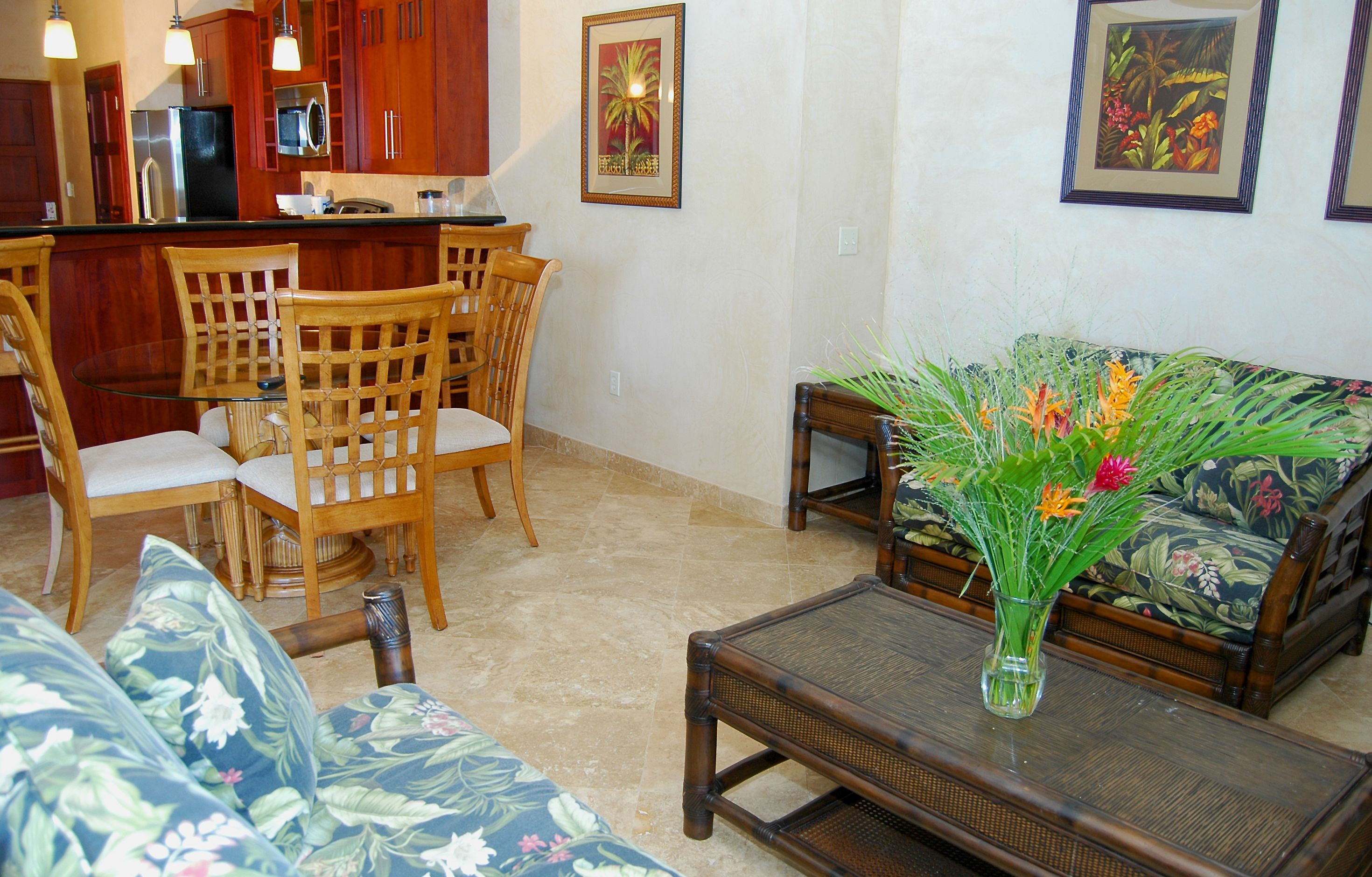 A living room with a sofa, chairs, a coffee table, and a kitchen area with wooden cabinets and a refrigerator.