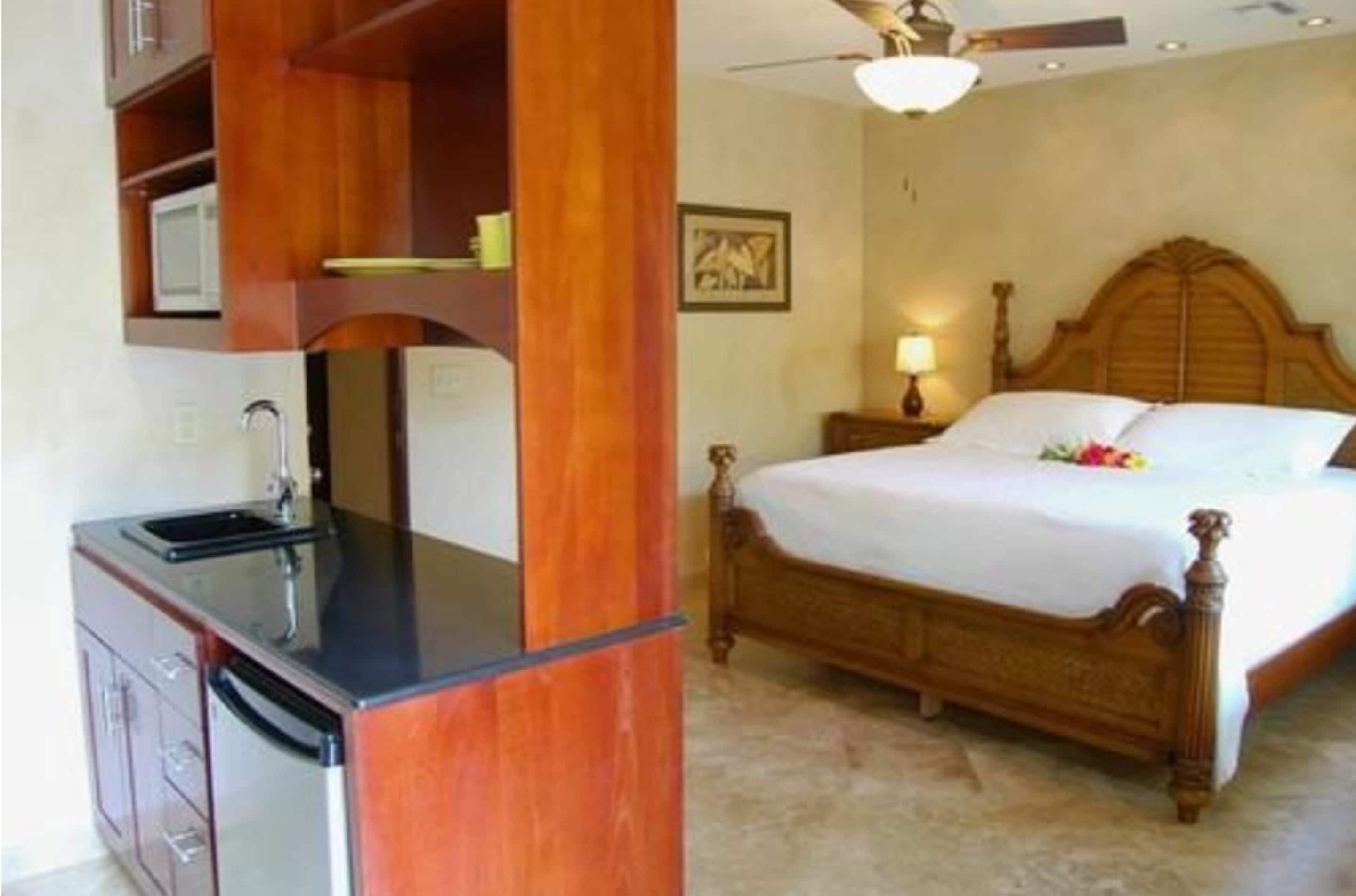 A bedroom with a wooden bed, a nightstand, a lamp, and a built-in microwave.