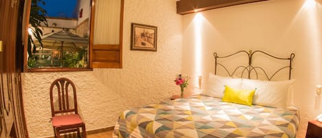 Um quarto com uma cama, uma cadeira, uma janela e uma porta.