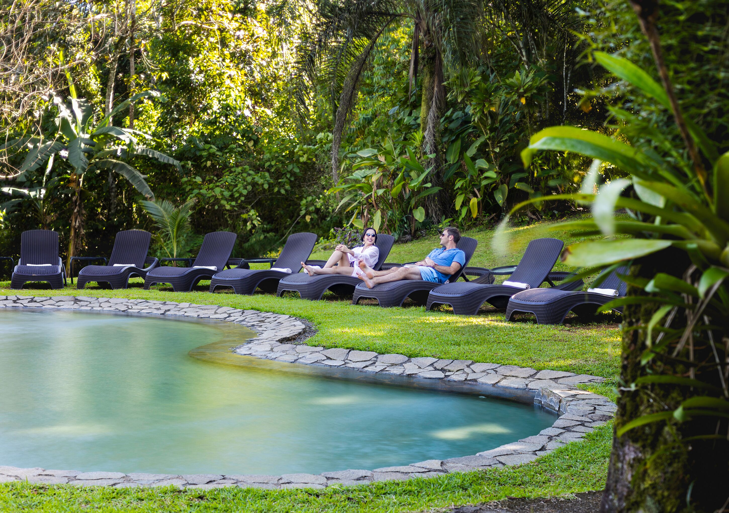 A pool area with lounge chairs and a stone border.