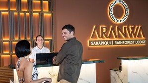 Un comptoir d’accueil avec une enseigne indiquant « ARANWA SARAPIQ | HÉBERGEMENT EN PLEINE FORÊT TROPICALE ».