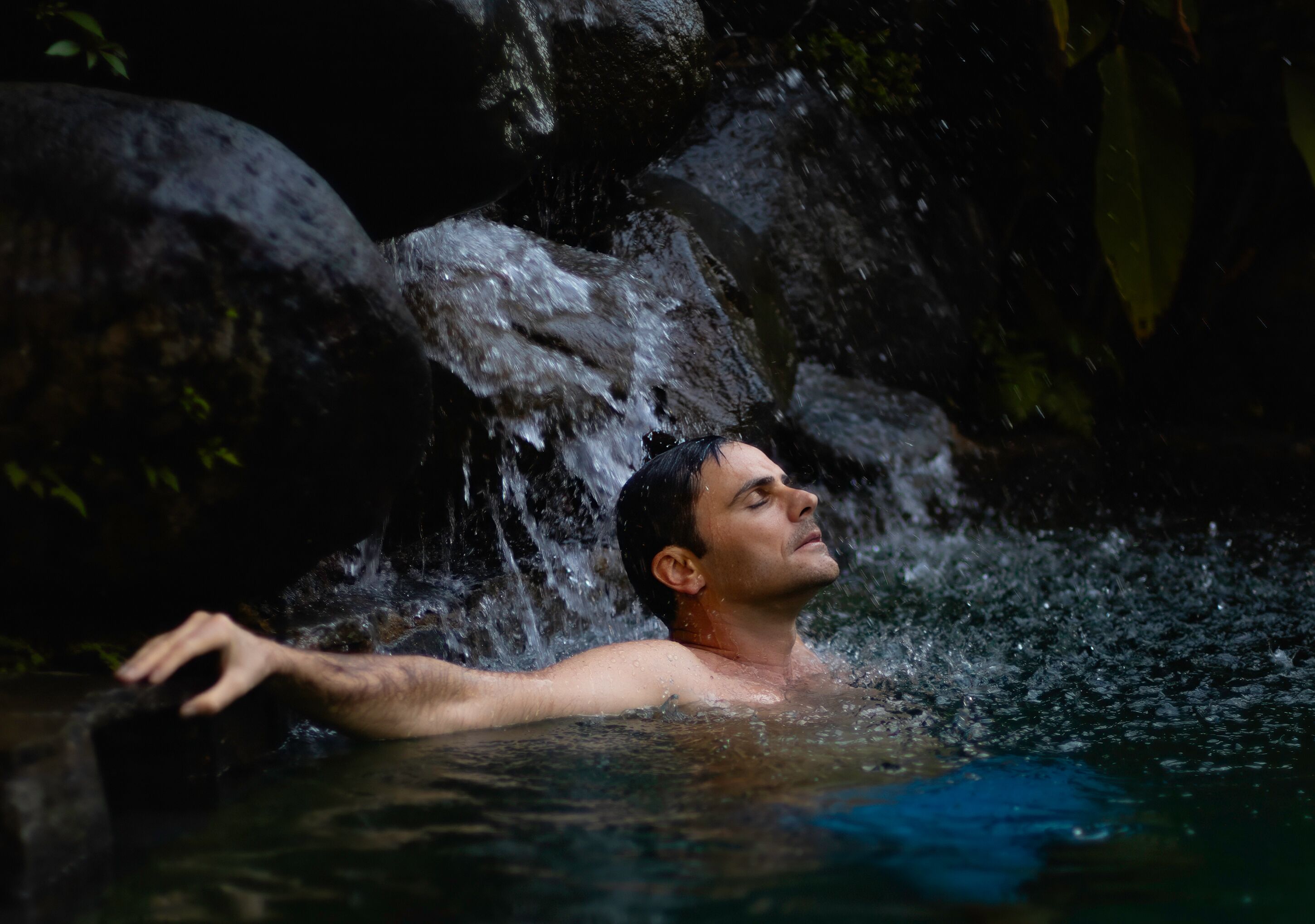 A person in a natural setting with water flowing over rocks.