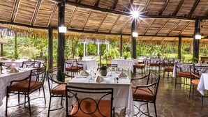 Un restaurant en plein air, avec des tables disposées pour accueillir les clients, entouré de verdure.