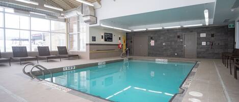 Una piscina interior con carriles claramente delimitados, una estación de socorrista y vistas al exterior a través de amplios ventanales.