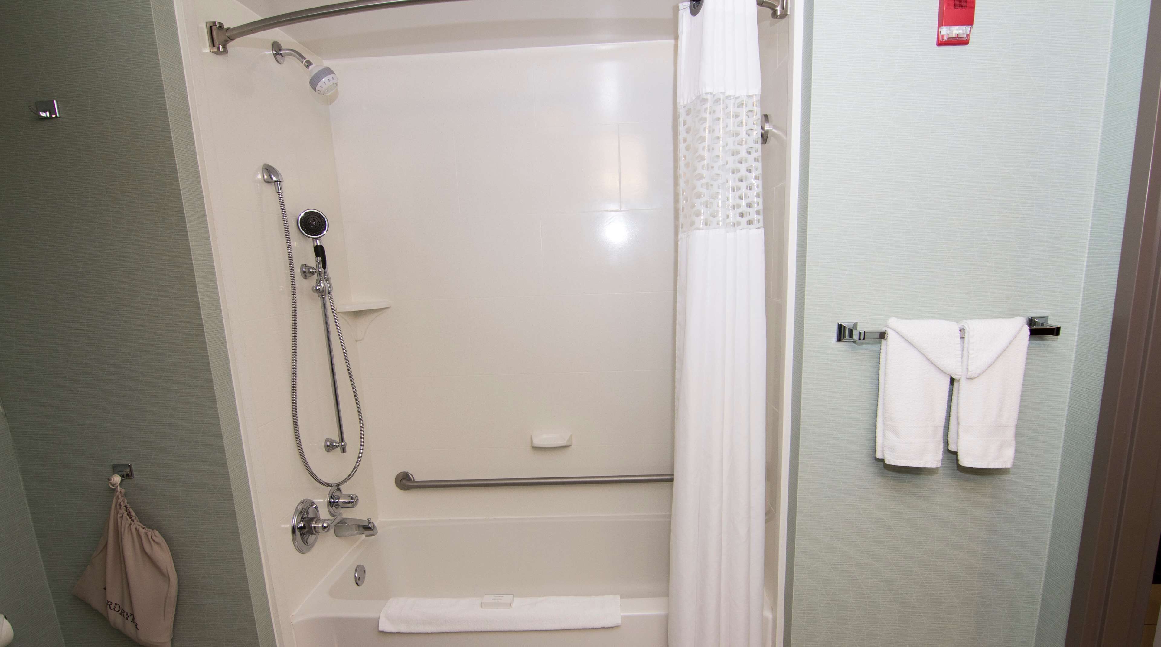 A modern bathroom with a walk-in shower, a bathtub, and a towel rack with towels.