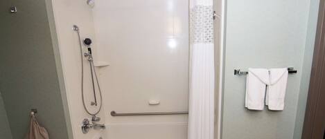 Un baño moderno con ducha a ras de suelo, bañera y un perchero con toallas.