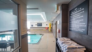 Un espace piscine équipé d’un poste de surveillance pour le sauveteur, d’un panneau indiquant les règles d’utilisation de la piscine et d’un porte-serviettes.