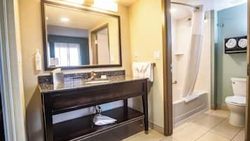 Une salle de bain avec un meuble-lavabo en bois foncé, un grand miroir, un lavabo, une douche et des toilettes.