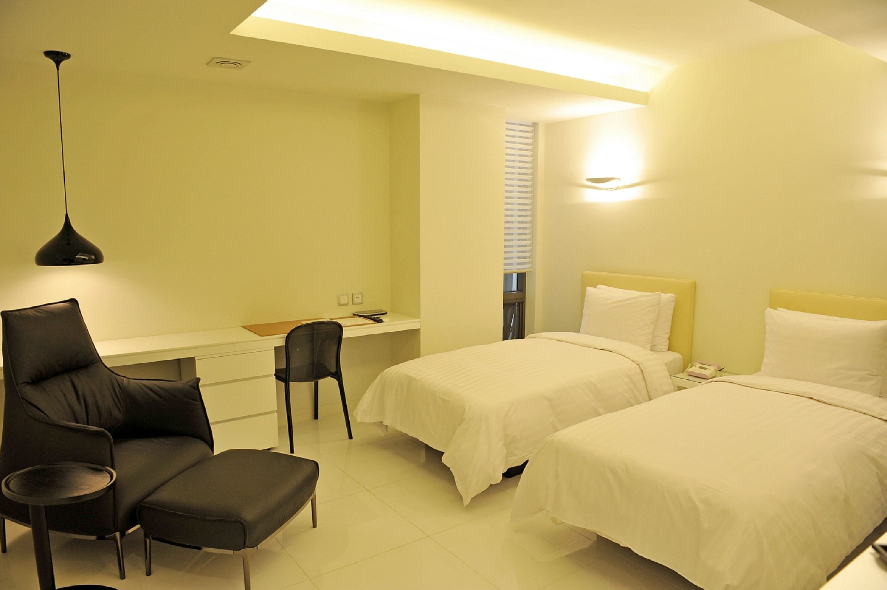 Una habitación de hotel con dos camas, un escritorio, una silla y una mesita.