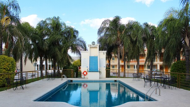 A swimming pool surrounded by palm trees and outdoor seating. - Comfort Inn Monterrey Norte (San Nicolas de los Garza)