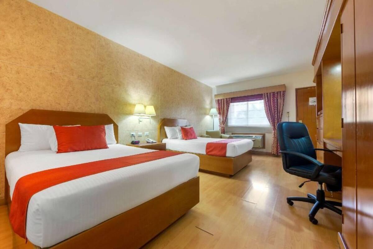 Una habitación de hotel con dos camas, un escritorio, una silla y un armario.