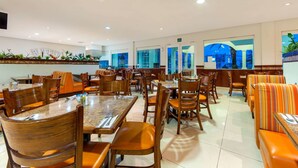 A spacious restaurant with multiple dining tables and chairs, a long counter, and a seating area with cushioned benches. - Comfort Inn Monterrey Norte (San Nicolas de los Garza)