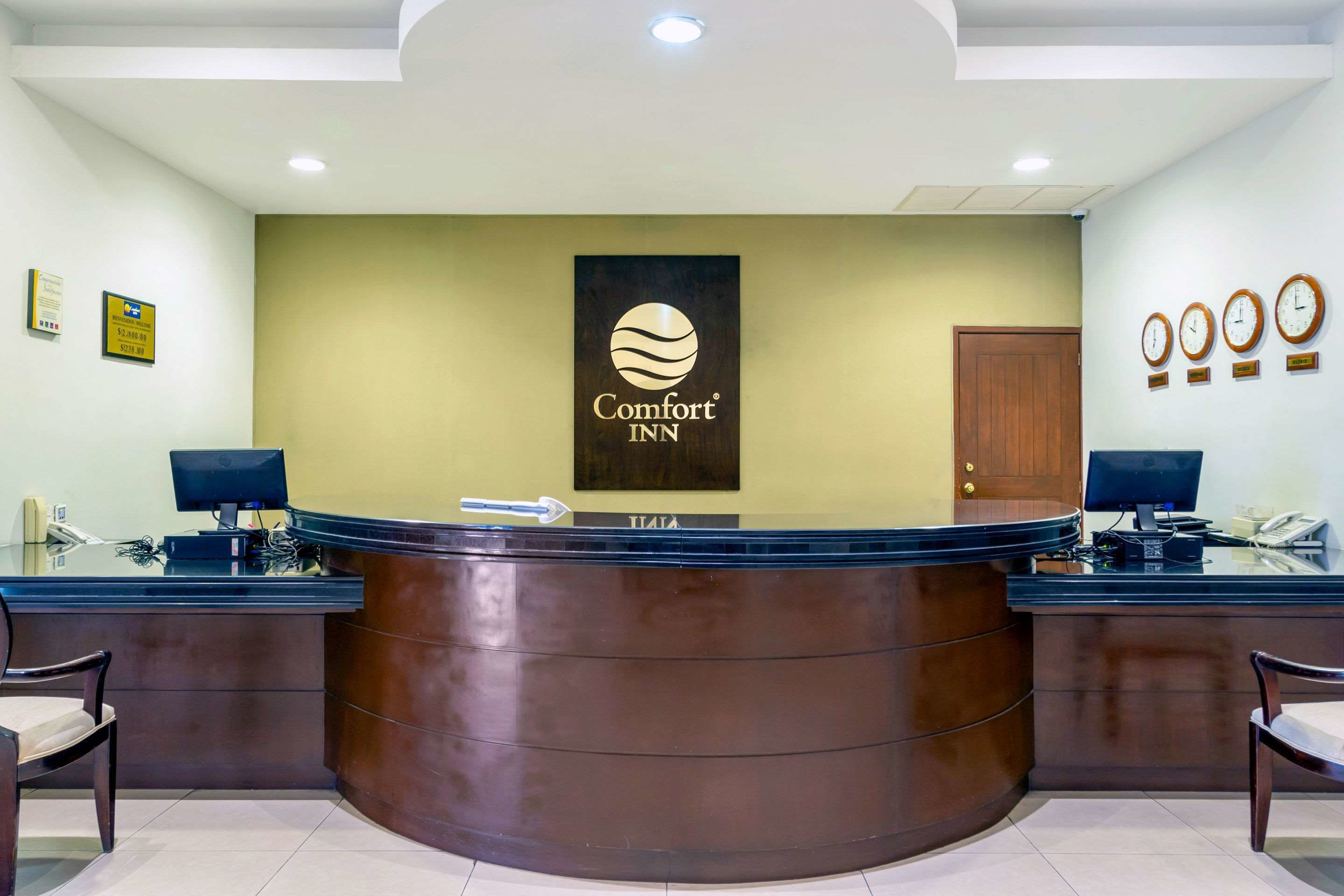 Un mostrador de recepción con el logotipo de Comfort INN, una puerta de madera y un reloj en la pared.